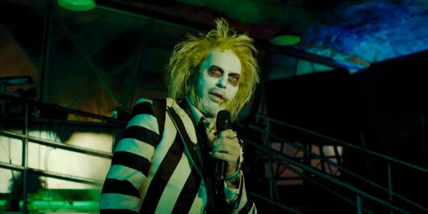 Michael Keaton as Beetlejuice telling his story with Delores on the microphone in Beetlejuice Beetlejuice